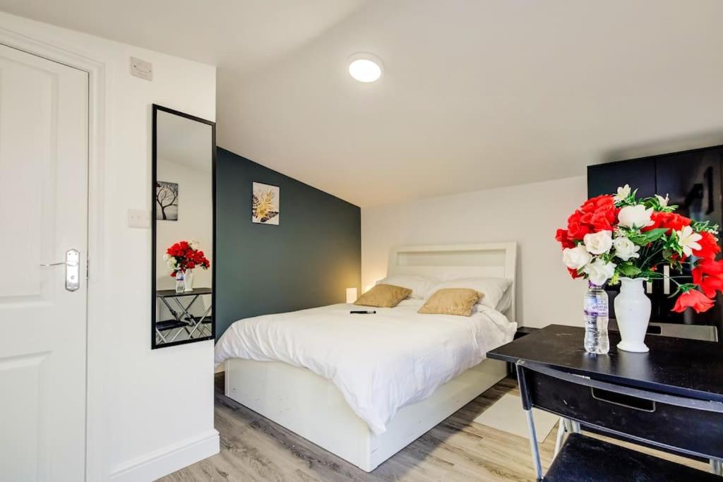 a bedroom with a bed and a desk with flowers on it at Luxury Studio Cabin - Central Location - Parking in Slades Green