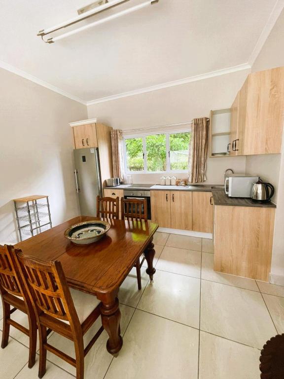a kitchen with a wooden table and wooden chairs at 3B Annie's Place Rawdons Country Estate in Nottingham Road
