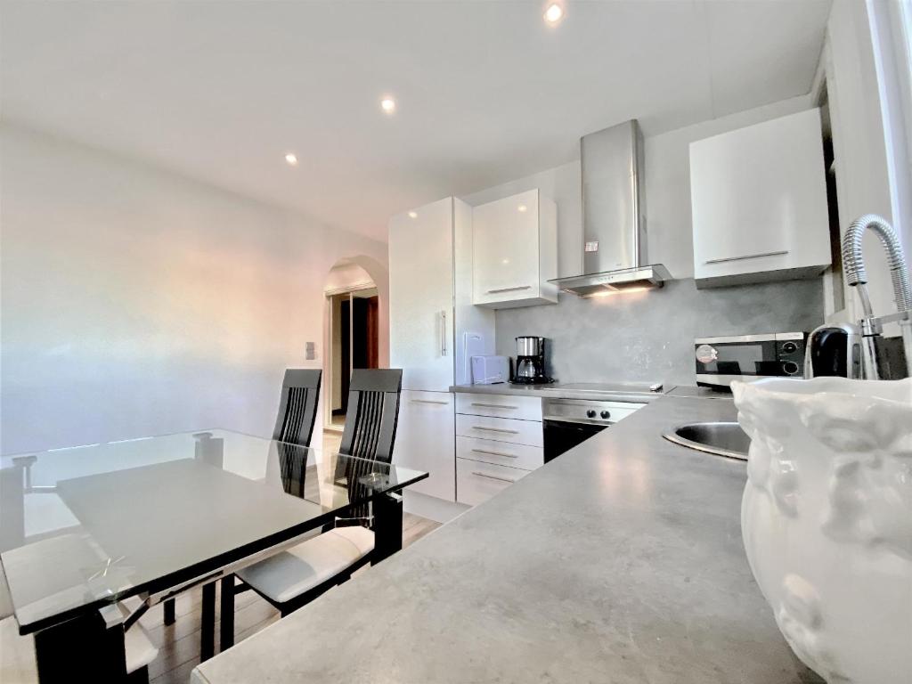 une cuisine avec des armoires blanches et une table avec des chaises dans l'établissement HENRY IV 2 pieces MES1112, à Cannes