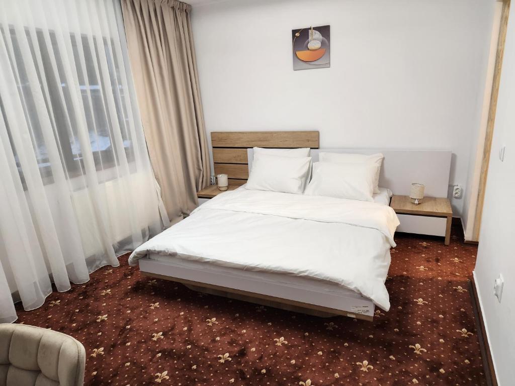 シナイアにあるHoliday Housesのベッドルーム1室(白いシーツと枕のベッド1台付)