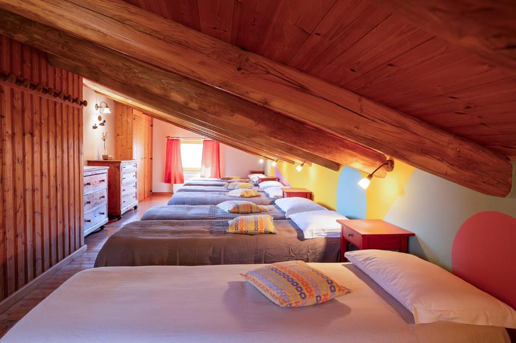 szereg łóżek w pokoju z drewnianym sufitem w obiekcie Agriturismo Fattoria Walden w mieście Ficulle