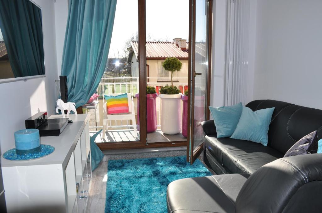 een woonkamer met een zwarte bank en een blauw tapijt bij Apartament Cristal in Karwia