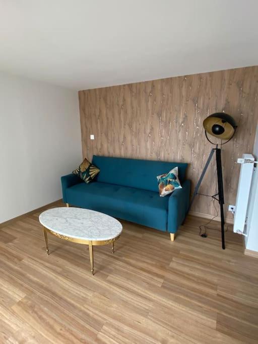 un salon avec un canapé bleu et une table dans l'établissement Appartement T2 entier, à Corps-Nuds