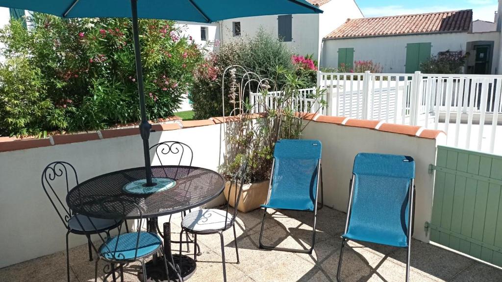 Un patio con una mesa y sillas y una sombrilla. en Appartement Océanis avec Piscine proche du port, en Saint-Martin-de-Ré