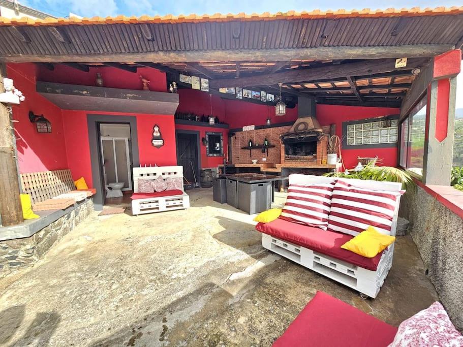 eine Außenterrasse mit einer roten Wand und eine Küche in der Unterkunft Refugio Jardim Prazeres WiFi BBQ in Prazeres