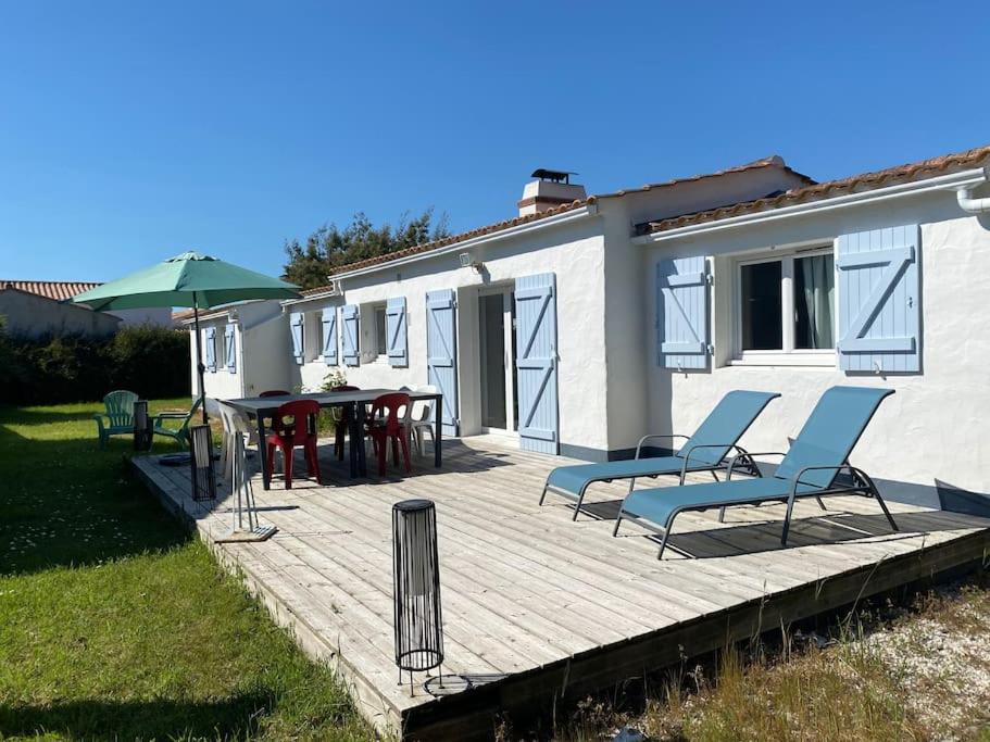 a wooden deck with chairs and a table and an umbrella at Maison située à 150m de la plage de la Madeleine in Noirmoutier-en-l'lle