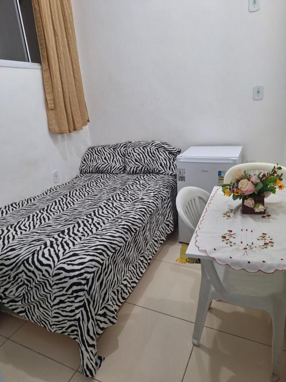 una stanza con un letto e un tavolo con una sedia di Linda Kitnet Mobiliada 03 a Salvador
