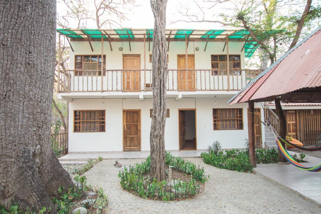 a white building with a balcony and two trees at The Ceiba House in Rivas