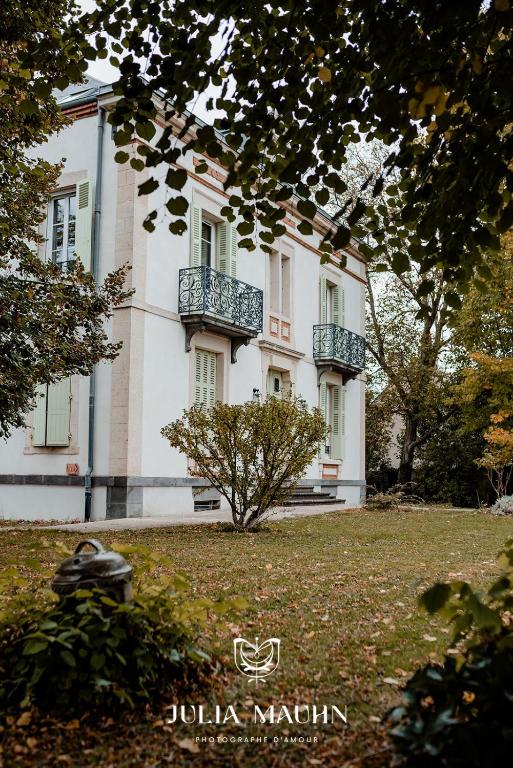 un grand bâtiment blanc avec des balcons sur une pelouse dans l'établissement La Maison de l'Andelot, à Monteignet-sur-lʼAndelot