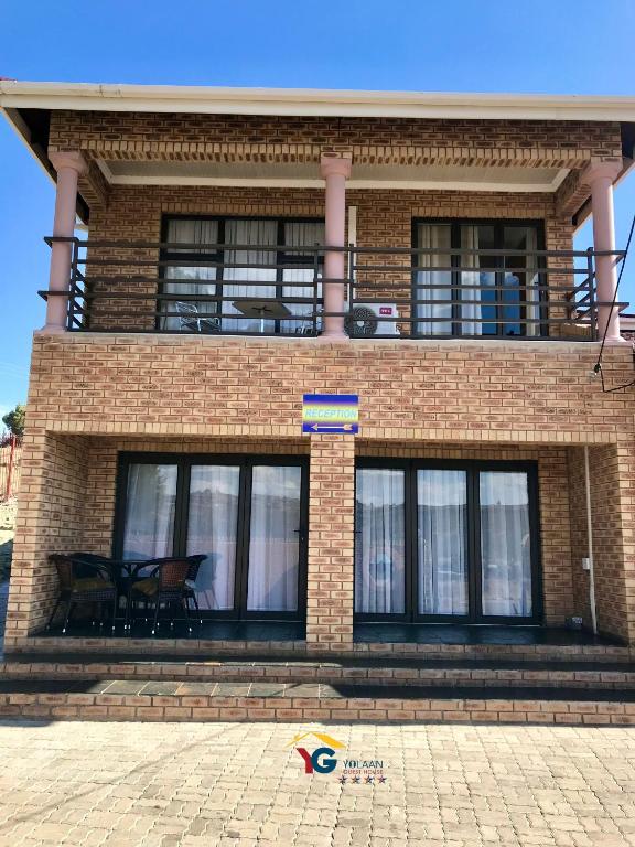 a brick building with a balcony on top of it at Yolaan Guesthouse in Sterkspruit