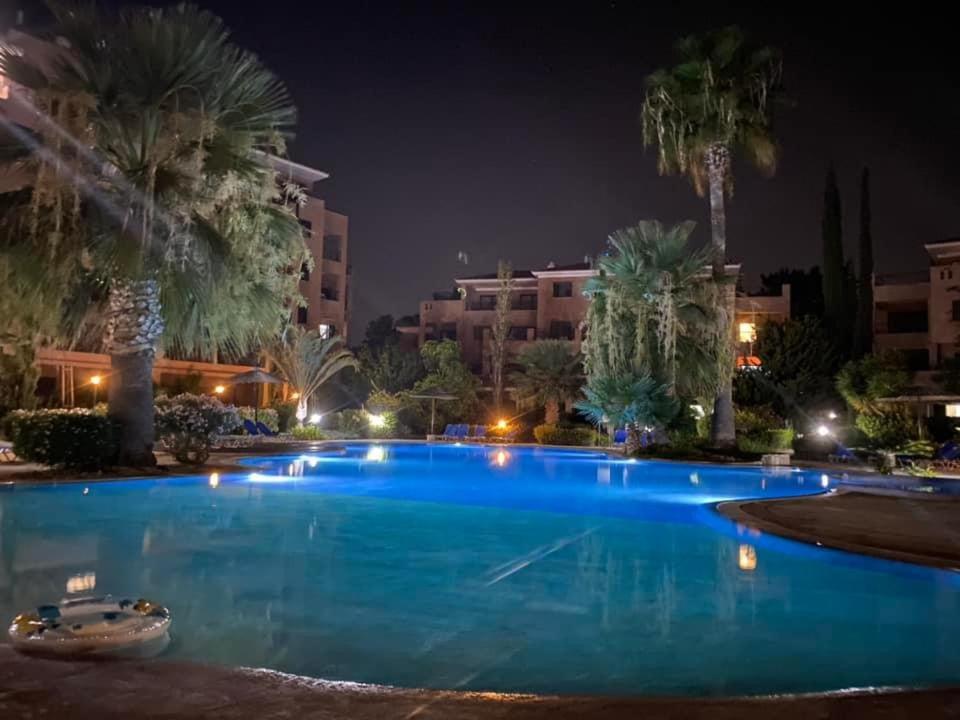 a large swimming pool with palm trees at night at Aphrodite gardens 2 bedroom in Paphos City
