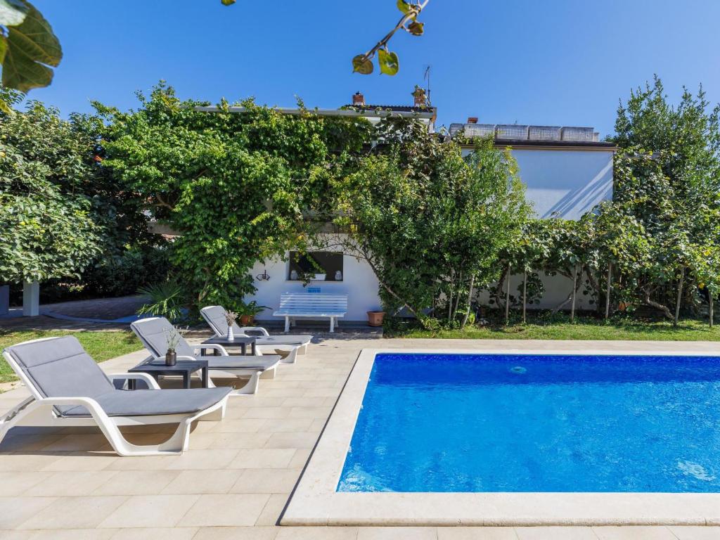 a swimming pool with lounge chairs next to a house at Holiday Home Villa Toni by Interhome in Umag