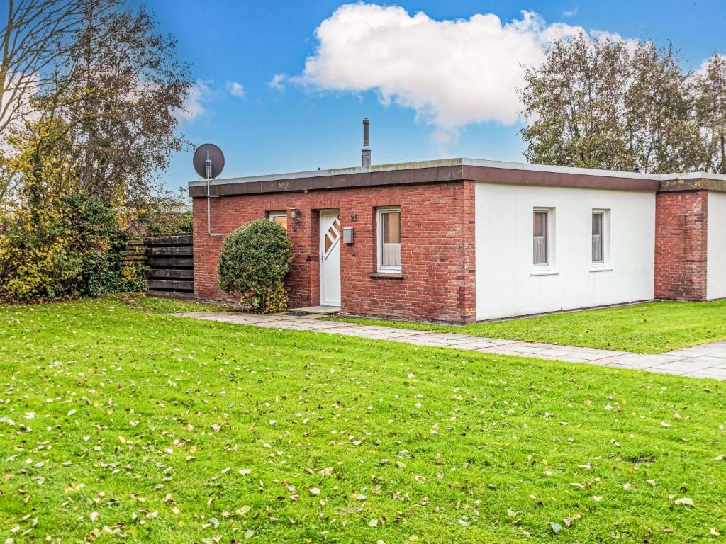 a small brick house with a grassy yard at Holiday Home Kiel by Interhome in Norddeich