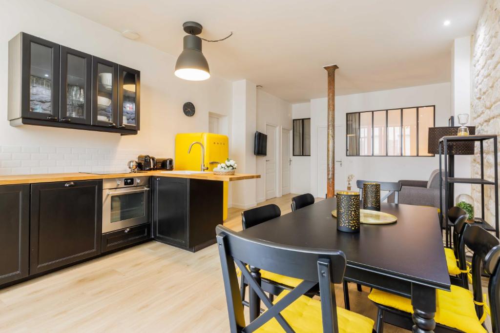 une cuisine et une salle à manger avec une table et des chaises noires dans l'établissement Loft Épuré et Confortable - 6 Pers Voltaire - 11e, à Paris