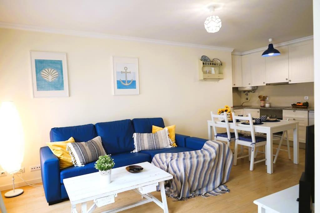 a living room with a blue couch and a kitchen at Fonte do Cabo Apartment in Ericeira