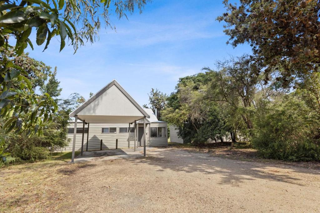 una casa blanca con árboles delante en Steamer - Waterfront Retreat, en Goon Nure