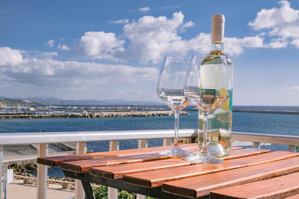 a bottle of wine and two glasses sitting on a wooden table at Appartamento Mare Blu in Sciacca