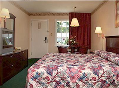Yorktown Motor Lodge في يوركتاون: غرفة نوم بسرير وخزانة وتلفزيون