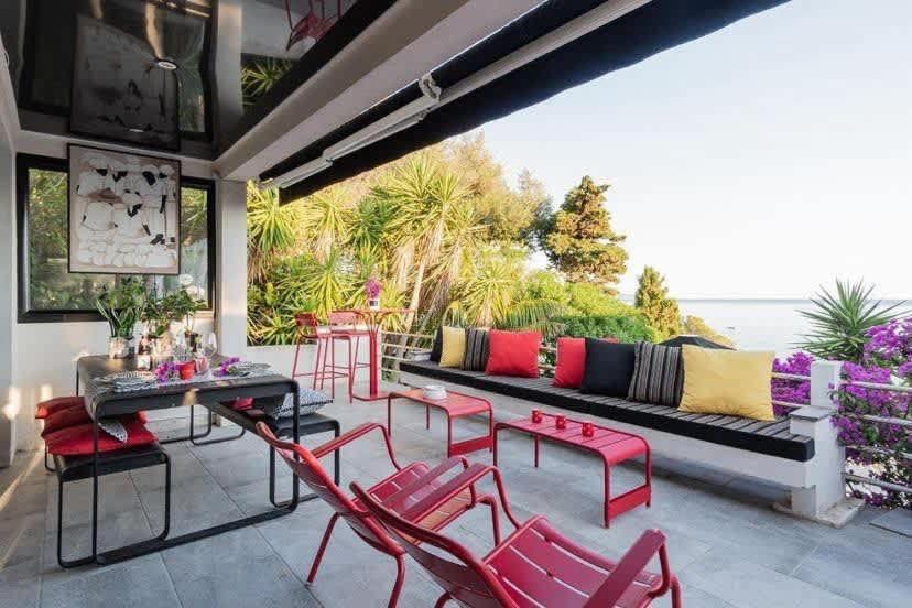 a patio with a couch and red chairs at Casamea - Villa, Piscine, Vue Mer, Sanguinaires in Ajaccio