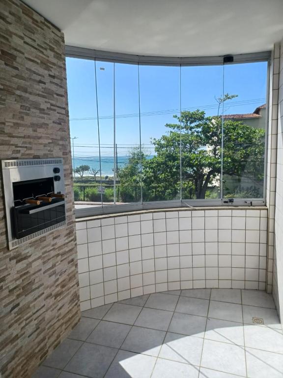 a room with a fireplace and a large window at Novidade na Enseada Azul! Apto com churrasqueira, área gourmet e Ar condicionado a 150m da praia in Guarapari