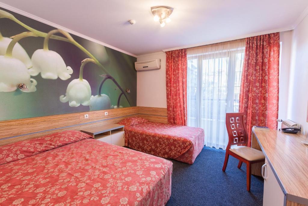 Habitación de hotel con 2 camas, escritorio y ventana en Семеен Хотел Опера, en Burgas