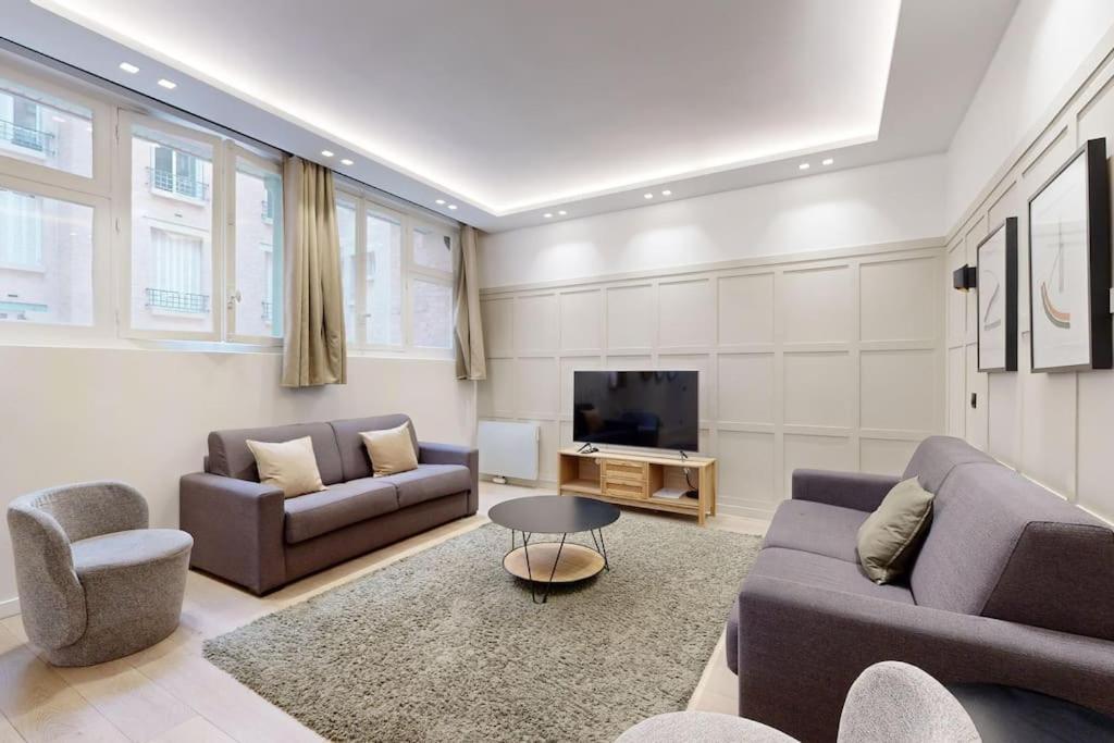 un salon avec deux canapés et une télévision dans l'établissement Sublime Paris apartment 3Br-10P, à Paris
