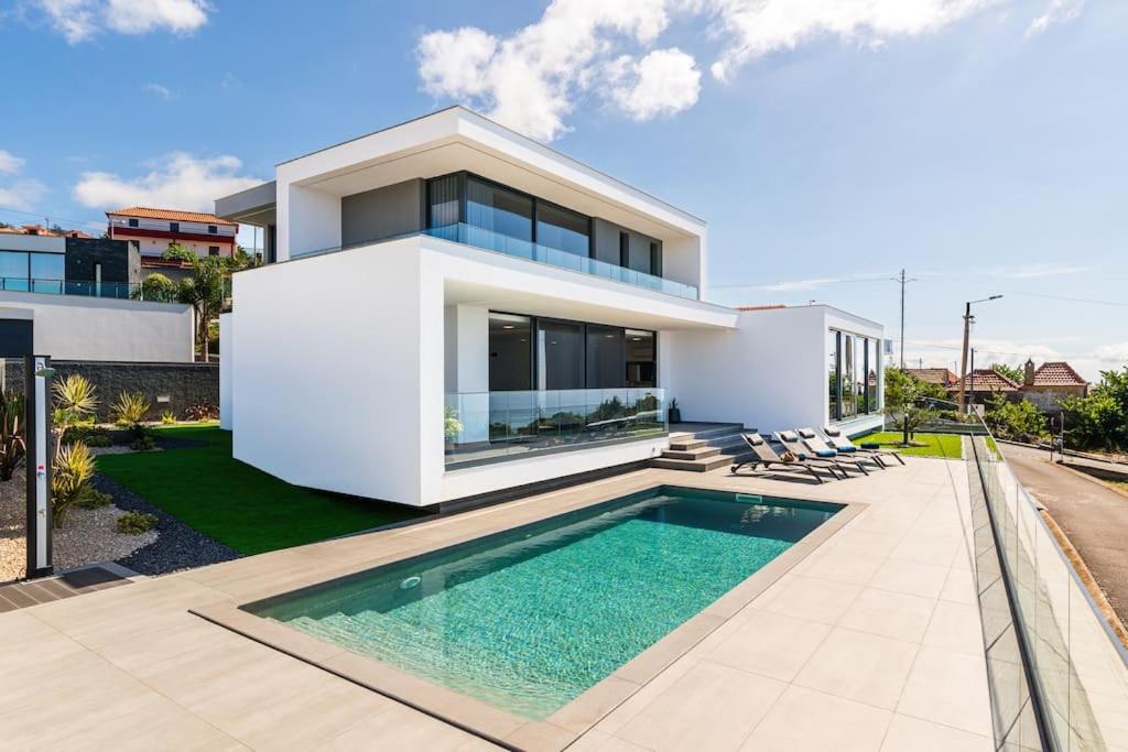 a white house with a swimming pool in front of it at Villa Lunarenzo seaview, Pool, AC, parking in Calheta