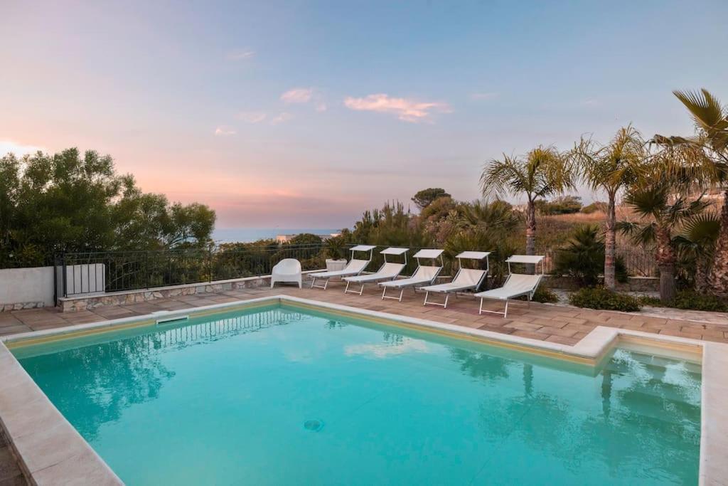 una piscina con sedie a sdraio e una piscina di Villa con Piscina 150mt dal Mare 8 Posti OA ad Alcamo
