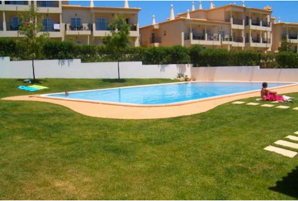 una persona sentada en el césped junto a una piscina en Akisol Albufeira Aqua II, en Albufeira