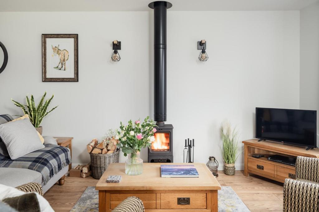 un soggiorno con camino e divano di Tawny Lodge Aviemore at Caledonian Escapes ad Aviemore