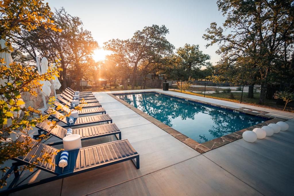 a swimming pool with lounge chairs and the sun setting at ParcBlu in Fredericksburg