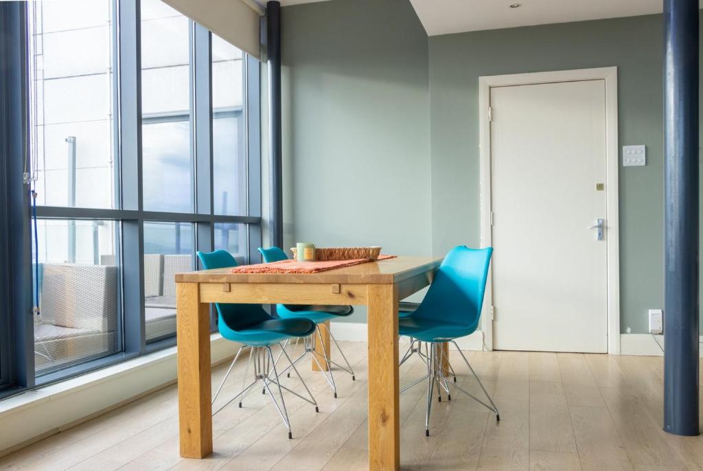a dining room with a wooden table and blue chairs at GuestReady - Enchanting views from Millenium Tower in Dublin