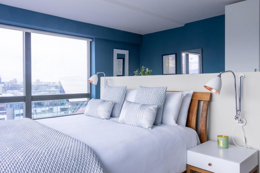 a bedroom with blue walls and a white bed with pillows at GuestReady - Enchanting views from Millenium Tower in Dublin