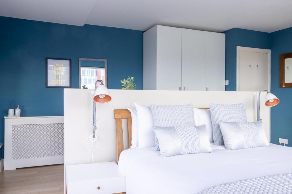 a bedroom with a white bed with blue walls at GuestReady - Enchanting views from Millenium Tower in Dublin