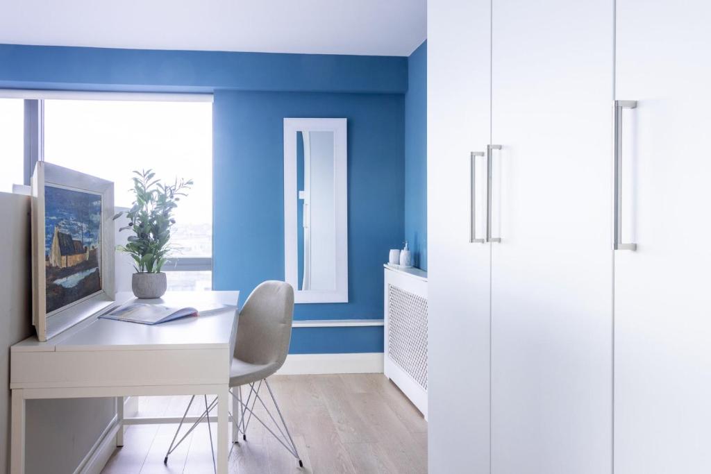 a room with a white desk and a blue wall at GuestReady - Enchanting views from Millenium Tower in Dublin