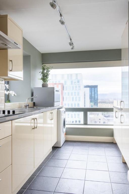 a kitchen with white appliances and a large window at GuestReady - Enchanting views from Millenium Tower in Dublin