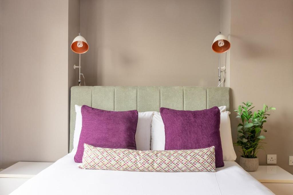 a bed with purple and white pillows and two lamps at GuestReady - Enchanting views from Millenium Tower in Dublin