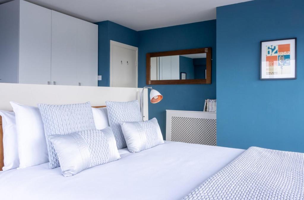 a bedroom with blue walls and a bed with white pillows at GuestReady - Enchanting views from Millenium Tower in Dublin