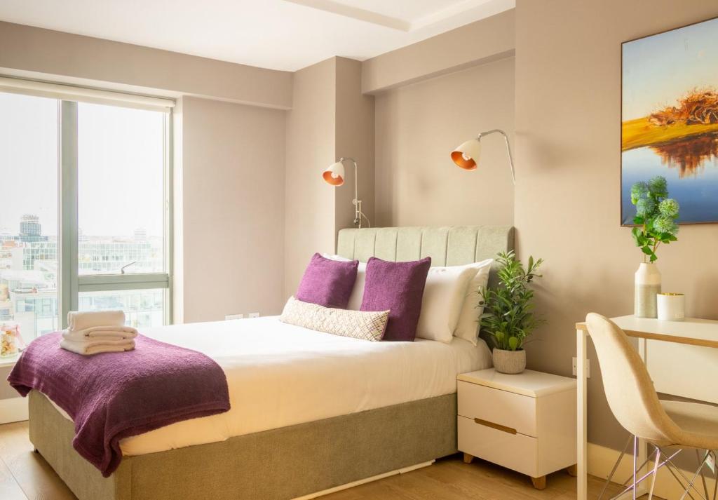 a bedroom with a bed with purple pillows and a desk at GuestReady - Enchanting views from Millenium Tower in Dublin