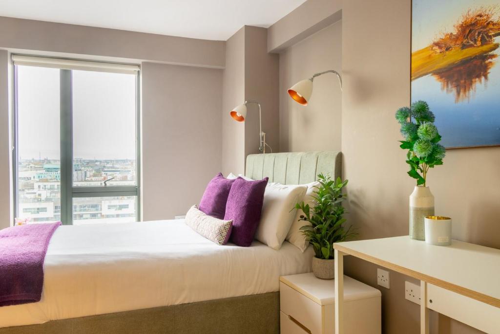 a bedroom with a bed with purple pillows and a window at GuestReady - Enchanting views from Millenium Tower in Dublin