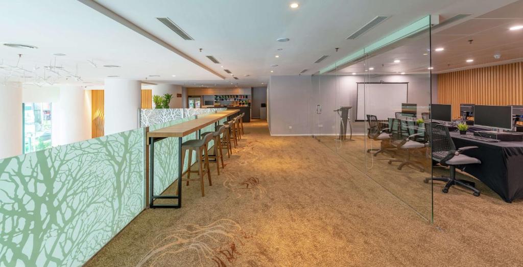 A modern event or meeting area with a bar counter, communal seating, and a glass-walled office zone.