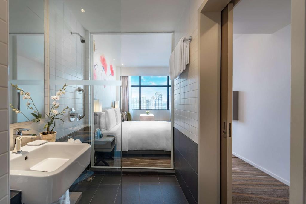 A compact bathroom with a vanity and glass-enclosed shower beside the bedroom.