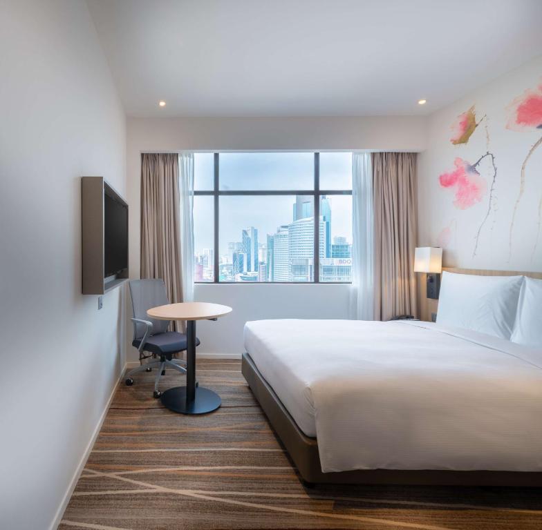 A compact king room with a large city-facing window and a small work table.