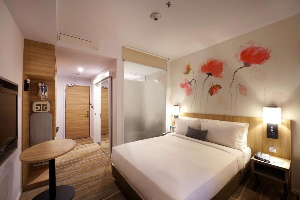 A warmly lit king room with a small table, minibar area, and frosted bathroom partition.