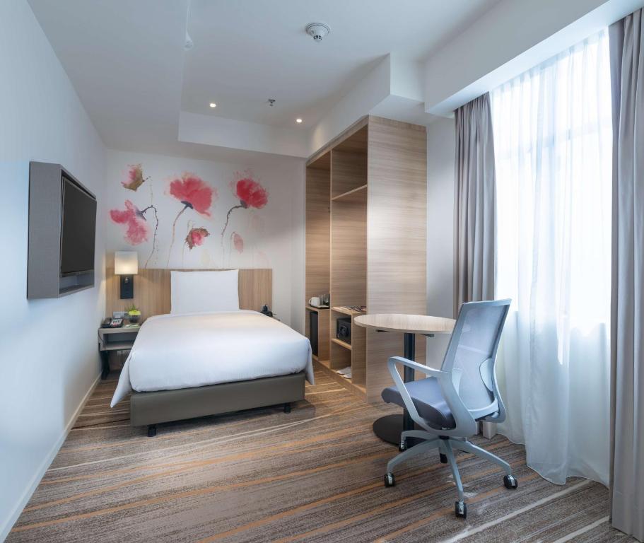 A compact single-bed room with a work desk beside a full-height curtained window.