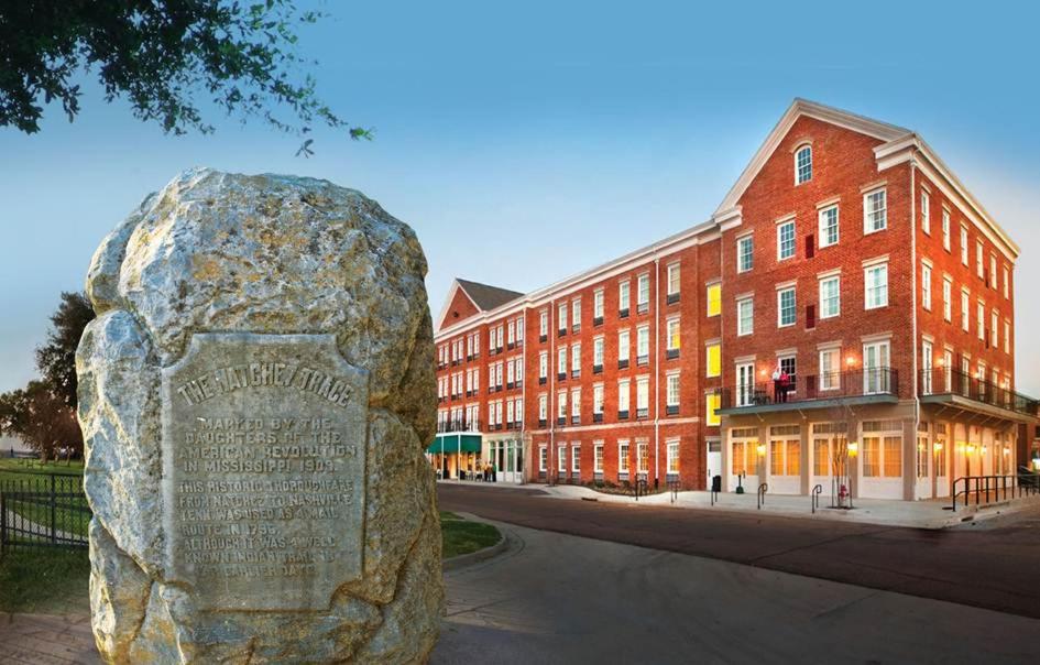 una estatua de piedra frente a un edificio de ladrillo en Natchez Grand Hotel On The River en Natchez