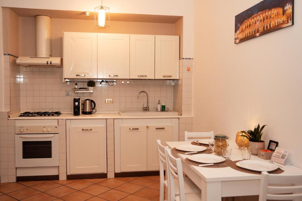 una cucina con armadi bianchi e tavolo con sedie di Residenza Longhena a Verona