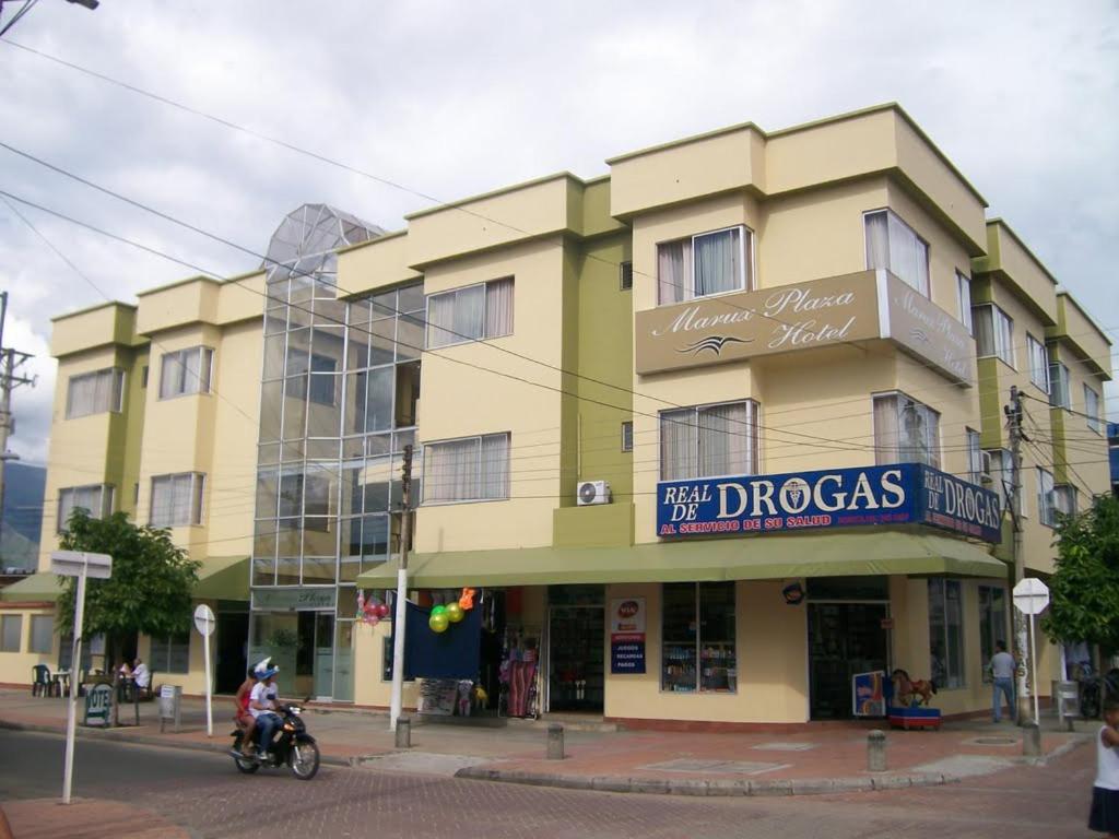 a yellow building on a street with a person on a motorcycle at Hotel Marux Plaza in Melgar