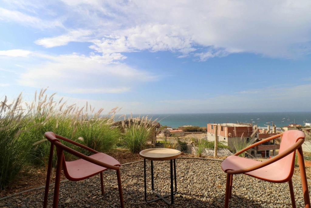two pink chairs and a table on top of the ocean at Casa Kahu by Wynwood House in Los Órganos