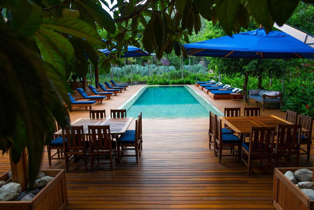 a pool with tables and chairs and blue umbrellas at Fazenda Shanti in Alto Paraíso de Goiás